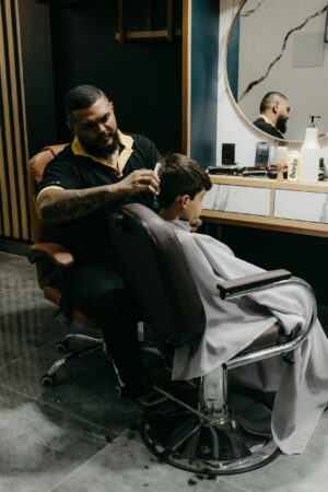 A skilled barber gives a young boy a stylish haircut in a contemporary barbershop setting. A skilled barber gives a young boy a stylish haircut in a contemporary barbershop setting.