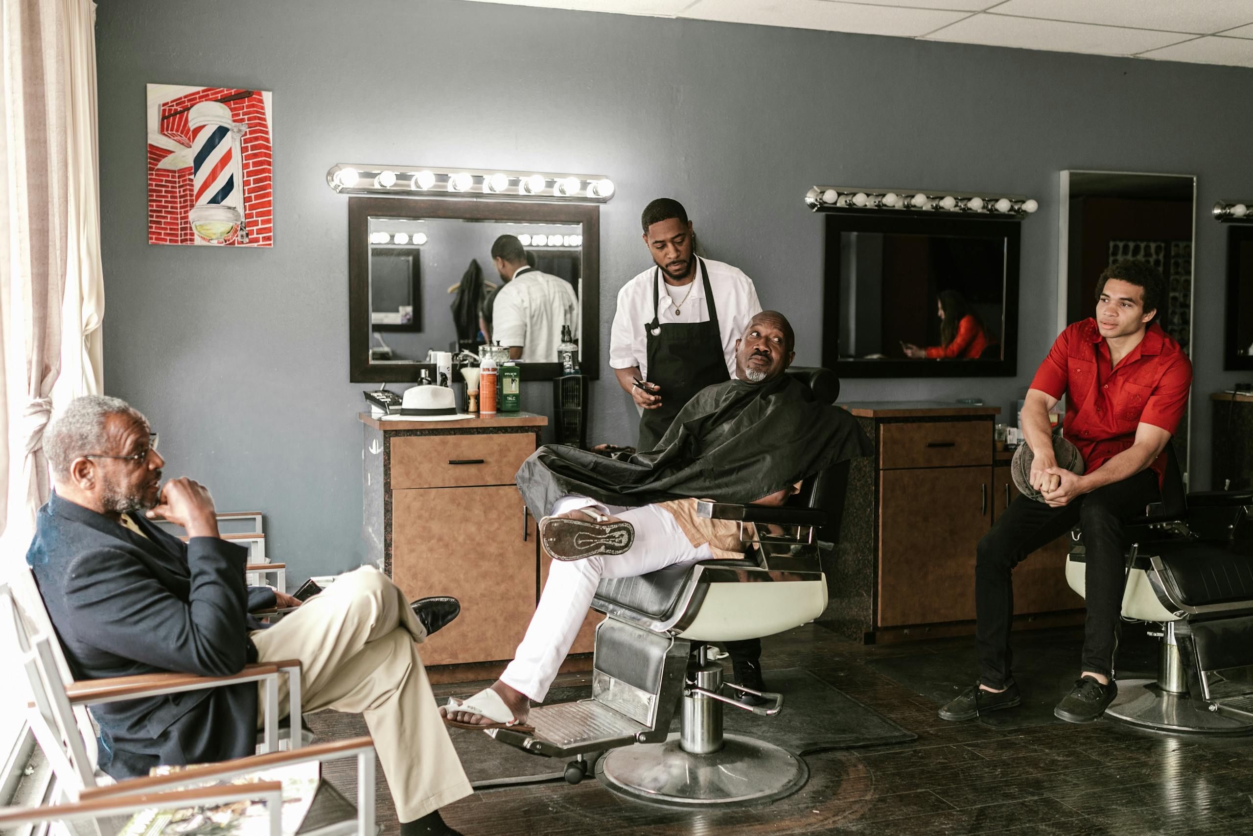 A stylish barber shop with clients and a barber in a relaxed setting, showcasing a classic grooming experience. A stylish barber shop with clients and a barber in a relaxed setting, showcasing a classic grooming experience.
