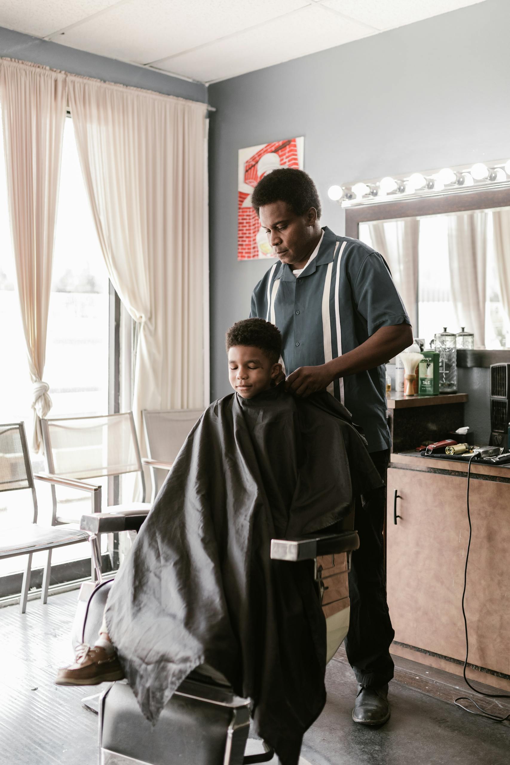 A young boy receives a haircut from a barber in a modern salon setting, showcasing a typical salon experience. A young boy receives a haircut from a barber in a modern salon setting, showcasing a typical salon experience.
