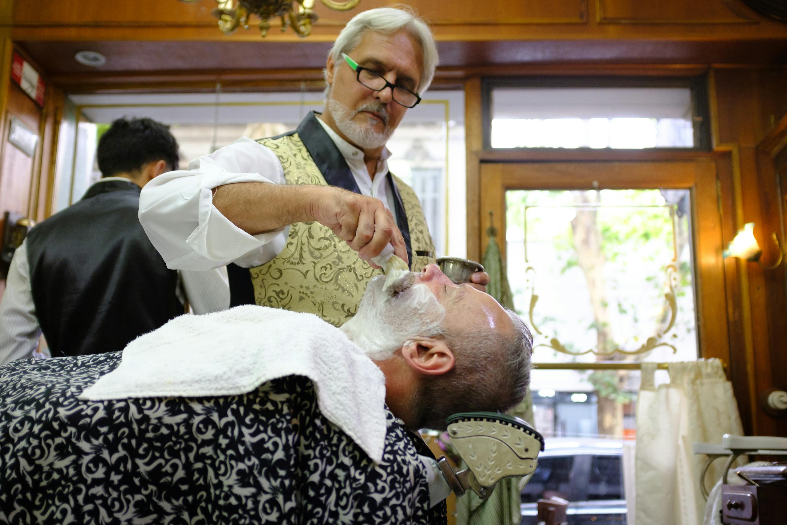 Barber giving a traditional hot towel shave in Buenos Aires barbershop. Barber giving a traditional hot towel shave in Buenos Aires barbershop.